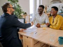 黑人企业主坐在桌旁与银行家握手